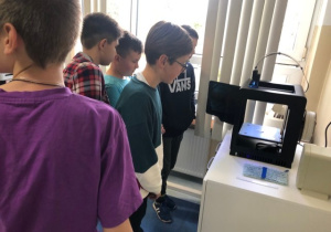 Uczniowie koła informatycznego CMI obserwują jak drukuje drukarka 3D