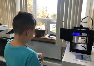 Uczniowie koła informatycznego CMI obserwują jak drukuje drukarka 3D