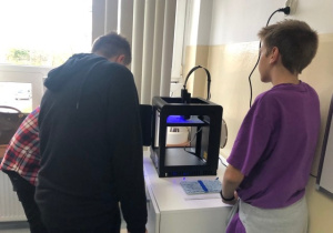 Uczniowie koła informatycznego CMI obserwują jak drukuje drukarka 3D