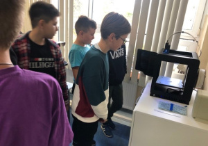 Uczniowie koła informatycznego CMI obserwują jak drukuje drukarka 3D
