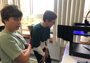 Uczniowie koła informatycznego CMI obserwują jak drukuje drukarka 3D