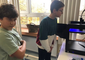 Uczniowie koła informatycznego CMI obserwują jak drukuje drukarka 3D