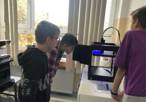 Uczniowie koła informatycznego CMI obserwują jak drukuje drukarka 3D