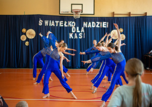 Grupa taneczna podczas występu. W tle napis "Światełko nadziei dla Kasi"