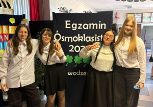 Na zdjęciu uczennice klas ósmych pozują na tle plakatu.