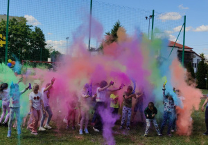 Uczniowie obrzucają się kolorowymi proszkami holi.