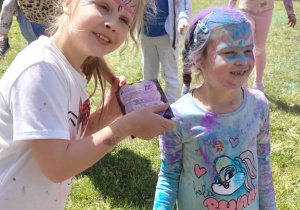 Uczniowie obrzucają się kolorowymi proszkami holi.