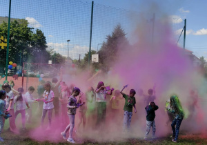 Uczniowie obrzucają się kolorowymi proszkami holi.