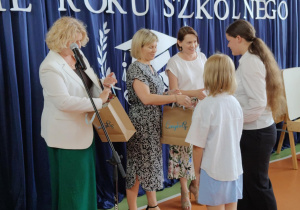 Nauczyciele wręczają uczennica nagrody.