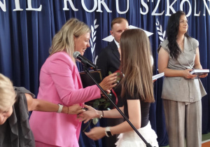 Wychowawca wręcza świadectwo uczennicy.