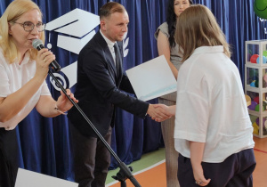 Dyrektor Biura Edukacji wręcza świadectwo uczennicy klasy ósmej.