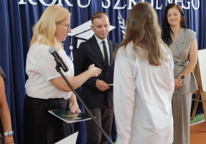 Wychowawca wręcza świadectwo uczennicy.