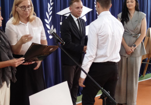 Dyrektor Biura Edukacji wręcza świadectwo uczniowi klasy ósmej.