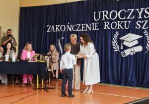 Wychowawca wręcza świadectwo uczennicy.