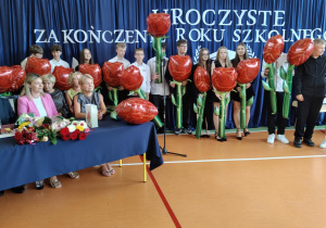 Uczniowie klas ósmych z kwiatami.