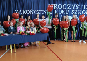 Uczniowie klas ósmych z kwiatami.