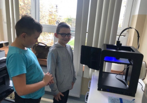 Uczniowie koła informatycznego CMI obserwują jak drukuje drukarka 3D