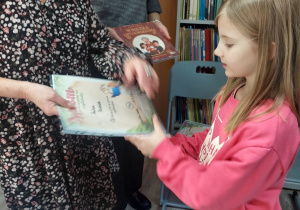 Nauczyciel wręcza uczennicy dyplom